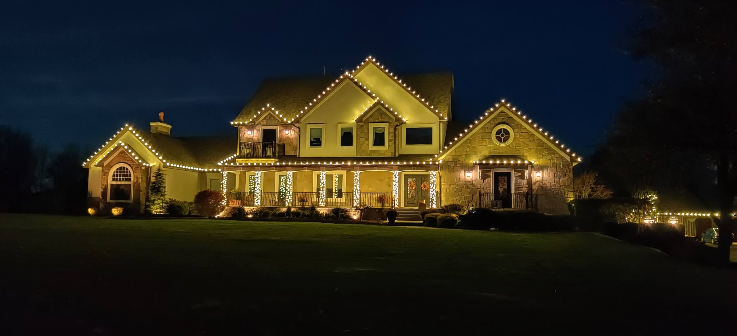 Large home with warm white roofline lights at night